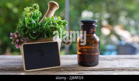 Flasche aus ätherischem Öl aus Citronella Geranium und leeres Etikett auf dem Holztisch, Nahaufnahme. Aromatherapie-Öl, Mückenschutz, Unschärfe Natur backg Stockfoto
