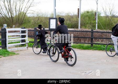 Orthodox-jüdische Jungen auf dem Fahrrad auf dem Radweg durch das Tor im Walthamstow Wetlands Naturschutzgebiet in London, England, Großbritannien, FAHREN KATHY DEWITT Stockfoto