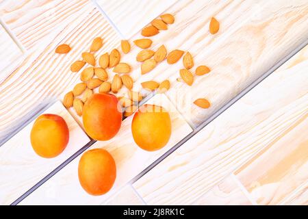 Frische reife Aprikosenfrüchte mit isolierten Körnern auf Holzgrund Stockfoto