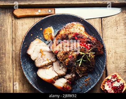 Leckerer gebratener Schweinebauch mit Gewürzen und Kräutern. Fettiges Stück Fleisch auf altem Tisch Stockfoto