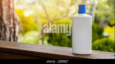 Weiße leere Düngerflasche auf Gartenhintergrund. Banner mit Kopierfläche Stockfoto