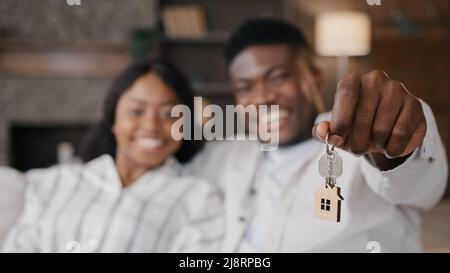 Verschwommene unfokussierte Ansicht afroamerikanisch verheiratetes Paar frisch verheiratete Frau und Mann, die Schlüssel für eine neue Wohnung halten, die mit Immobilien zufrieden ist. G Stockfoto