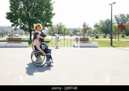 Zwei verschiedene kaukasische Freundinnen, die durch einen Stadtpark schlendern und miteinander reden Stockfoto