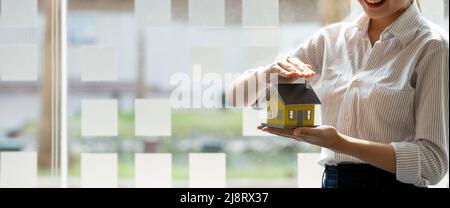 Beschnittene Ansicht des Risikomanagers schützendes Hausmodell. Hausversicherungskonzept. Stockfoto