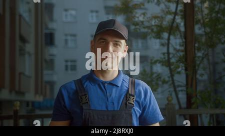 Glücklicher junger Lieferer Kurier im Tragen des blauen Hutes Stockfoto