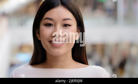 Asiatische Headshot glücklich optimistisch Millennial Mädchen 20s Brünette Frau mit natürlichen Make-up Geschäftsfrau Frau Freundin Lehrer Arbeiter dreht Kopf schaukig Stockfoto