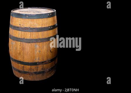 Altes Holz-Whiskey-Fass mit Metallumreifung auf schwarzem Hintergrund. Speicherplatz Kopieren. Stockfoto