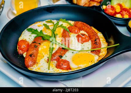 Komplettes irisches Frühstück mit Spiegelei, Würstchen, Tomaten in einer gusseisernen Pfanne Stockfoto