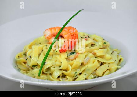 Italienische Pasta Fettuccine mit Garnelen in cremiger Sauce mit Parmesankäse und Thymian auf einem Teller Stockfoto