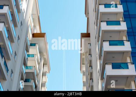 Blick zwischen den Gebäuden am Himmel mit einem vorbeifliegenden Flugzeug. Stockfoto