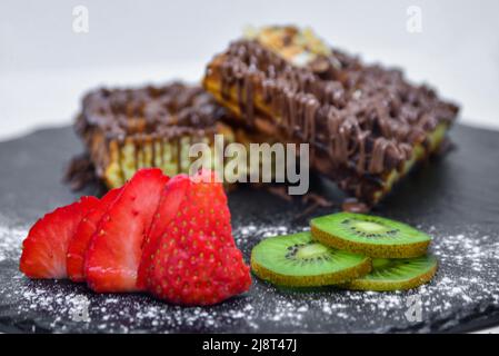 Ein köstlicher Waffelteller mit Erdbeere und Kiwi zum Garnieren Stockfoto