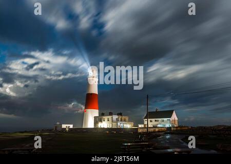Blitze eines vorbeiziehenden Gewitters erleuchten die Wolken am Nachthimmel über dem Leuchtturm von Portland Bill in Dorset. Bild: Graham Stockfoto