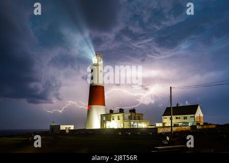 Blitze eines vorbeiziehenden Gewitters erleuchten die Wolken am Nachthimmel über dem Leuchtturm von Portland Bill in Dorset. Bild: Graham Stockfoto