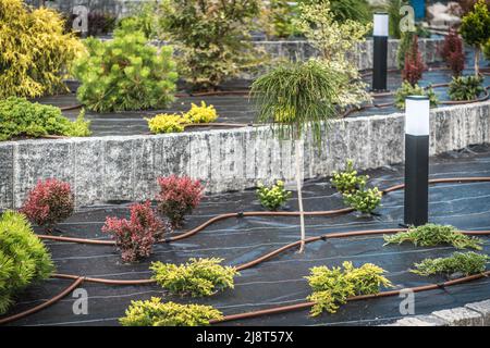 Professionell gemachte Wohn-Garten-Drip-Bewässerungssystem und Gartenbeleuchtung im Freien. Stockfoto