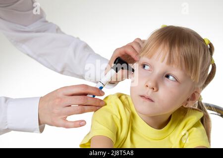 Der Arzt untersucht den Gehörgang eines kleinen Mädchens im Alter von 5 Jahren in der Arztpraxis. Diagnose und Behandlung von Ohrerkrankungen Stockfoto