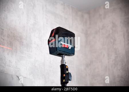 Bau-Laser-Ebene auf dem Hintergrund der Wand, Nahaufnahme. Werkzeug Für Glatte Beschichtung Stockfoto
