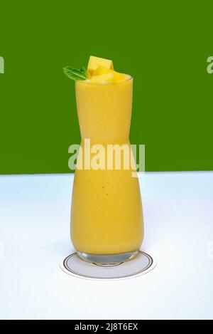 Mangosaft mit Mangostücken und Minze auf grünem Hintergrund Stockfoto