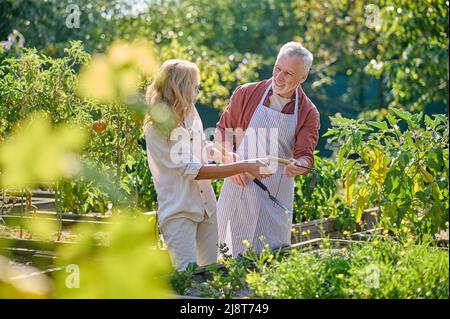 Mann und Frau mit Gartengeräten im Garten Stockfoto