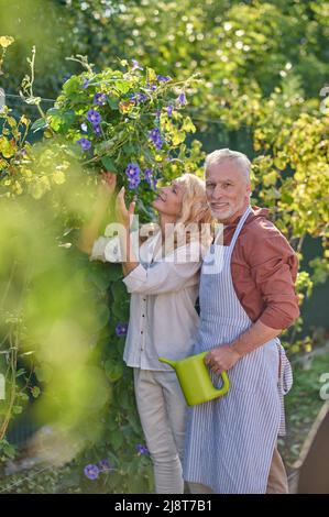 Mann umarmt Frau berührt Blumen im Garten Stockfoto