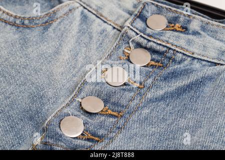 Stylische Knöpfe auf angesagtem Denim-Rock, Hintergrund, Makro. Stockfoto