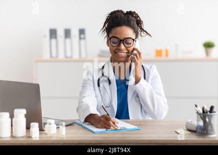 Porträt eines lächelnden Arztes, der in der Klinik telefoniert Stockfoto