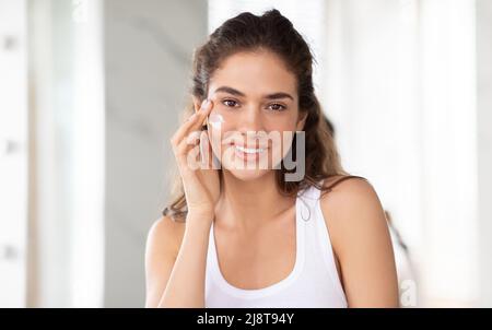 Portrait Einer Attraktiven Frau, Die Gesichtscreme Im Badezimmer Aufbringt Stockfoto