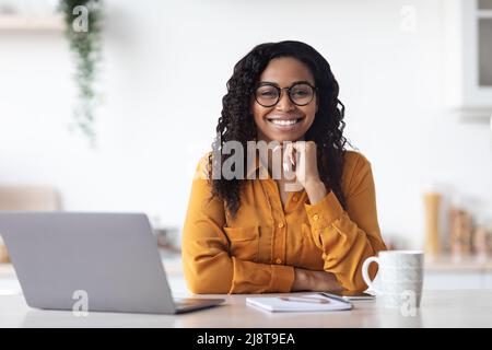 Porträt der schönen schwarzen Frau, die auf dem Laptop arbeitet Stockfoto