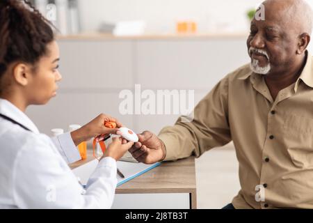 Notrufsystem. Der Arzt gibt dem älteren Mann die Alarmtaste Stockfoto