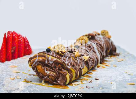 Pfannkuchen mit Erdbeeren und Nüssen, gekrönt mit Schokoladensauce, süßes Frühstück Stockfoto