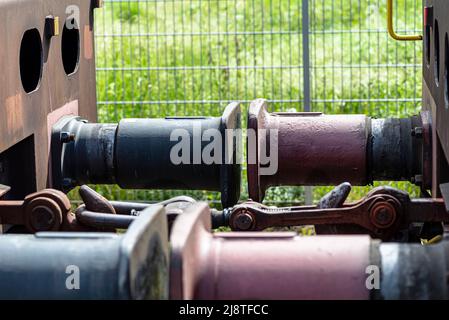 Kettenkupplung verbindet Güterwagen, große Wagenpuffer sichtbar. Stockfoto