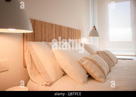 Nahaufnahme eines gemütlichen Apartment-Schlafzimmers mit Boho-Stil in Weiß- und Holzfarben Stockfoto