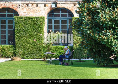 LUCCA, ITALIEN - 16. SEPTEMBER 2018: Eine nicht identifizierte ältere Frau ruht auf dem Rasen des alten Parks des Palazzo Pfanner. Stockfoto