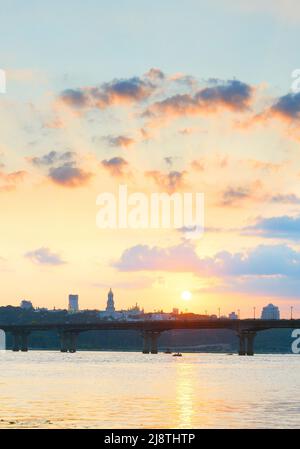 Blick auf den Sonnenuntergang über dem Mutterland-Denkmal, Motorboot auf dem Dnipro-Fluss, Paton-Brücke. Kiew, Ukraine Stockfoto