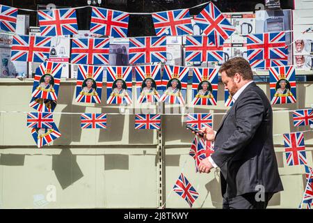 London, 18. Mai 2022. Eine Fußgängerin geht an einem Schaufenster im Stadtzentrum von Wimbledon vorbei, das mit Union Jack-Fahnen geschmückt ist und das Platinjubiläum feiert, da Königin Elizabeth 70 Jahre als die am längsten dienende britische Monarchie seit ihrer Thronbesteigung im Jahr 1952 feiert. Kredit. amer Ghazzal/Alamy Live Nachrichten Stockfoto