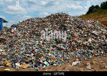 Riesiger Müllhaufen in der Recyclingfabrik unter dem Himmel mit Wolken Stockfoto