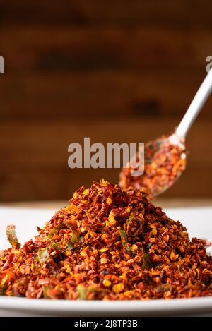 Rotes Chili-Sambol oder würziges Gewürz auf einem Teller mit einem Löffel, hergestellt aus Chilischoten und maldivischen Fischen, aufgenommen in geringer Tiefenschärfe, Nahaufnahme Stockfoto