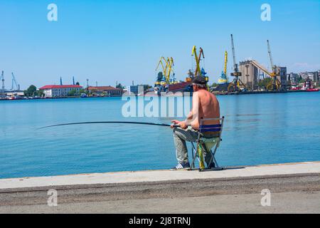 Seehafen in Burgas, Bulgarien. Foto des Anlegekai und der Hafenkrane an einem Sommertag. Fischer arbeiten in den Häfen vom Pier aus. Stockfoto