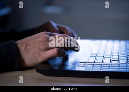 Man tippt auf einer Laptop-Tastatur, Hände aus der Nähe. Stockfoto