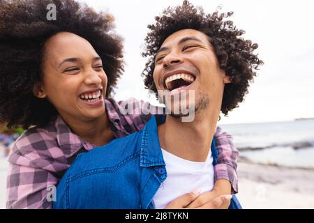 Verspieltes afro afroamerikanisches junges Paar, das am Strand genießt Stockfoto