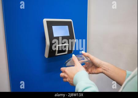 Preisscanner für Barcodes in Nahaufnahme an der Wand in einem Geschäft. Die gesichtslose Käuferin überprüft selbständig den Wert der Ware. Stockfoto