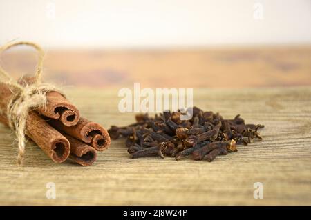 Nahaufnahme von weihnachtlichen Gewürzen. Zimtstangen mit Garn und Nelken auf altem Holzhintergrund gebunden. Speicherplatz kopieren. Stockfoto