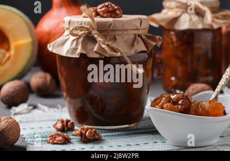 Hausgemachte Kürbismarmelade mit Zitrone und Walnüssen in Gläsern und Schüssel Stockfoto