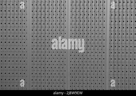Bild für industrielle und futuristische Hintergründe, die durch eine Metallplatte mit einem Muster aus Löchern und vertikalen Linien gebildet werden Stockfoto
