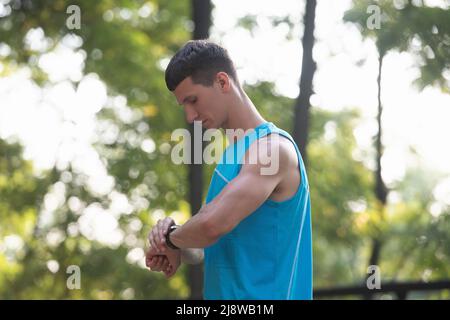 Mann Läuferin in Sportbekleidung, der die Zeit auf der Smartwatch überprüft Stockfoto