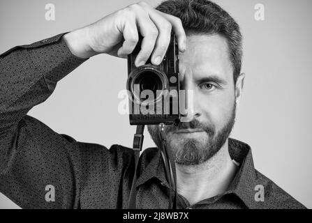 Fotograf mittleren Alters fotografieren mit Blick auf die handgeführte Fotokamera, Schnappschüsse. Stockfoto