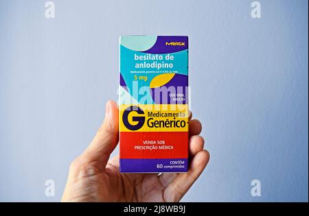 RIO DE JANEIRO, BRASILIEN - 21. APRIL 2022: Hand hält eine Schachtel mit (generischem) Amlodipin-Besylat, einem Medikament zur Kontrolle von Bluthochdruck Stockfoto