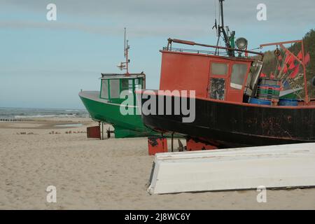 Alte Boote stehen am Strand am Meer, ein altes, sich abschälende Fischerboot steht am Ufer. Ein Fischernetz hängt an einem Boot. Die Textur des alten Holzes. Stockfoto