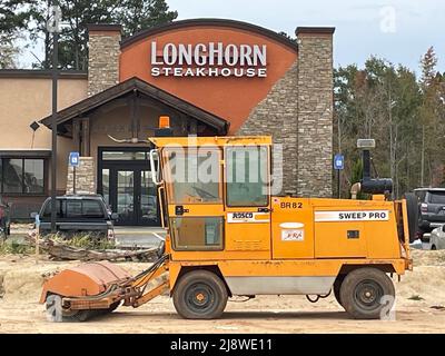 Augusta, GA USA - 04 15 22: Street Kehrmaschine und Longhorn Steakhouse im Hintergrund Stockfoto