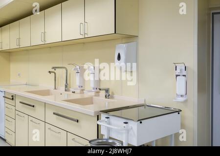 Ellenbogen Seife und antiseptischen Spender oder Desinfektionsmittel Wand zur Händedesinfektion und Wasserhahn Waschbecken mit Wasserhahn Bad oder Klinik montiert Stockfoto
