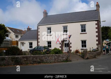 Ein großes Haus in St. Peters, Jersey, Channel Islands, das große Union Jack- und Jersey-Flaggen an beiden Seiten der Eingangstür zeigt, um den Befreiungstag zu feiern Stockfoto